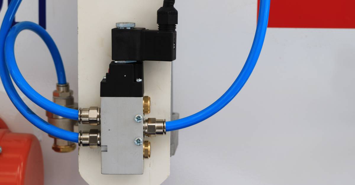 A working pneumatic valve. Two blue hoses attach to the left side of the valve, while one blue tube is attached to the right.