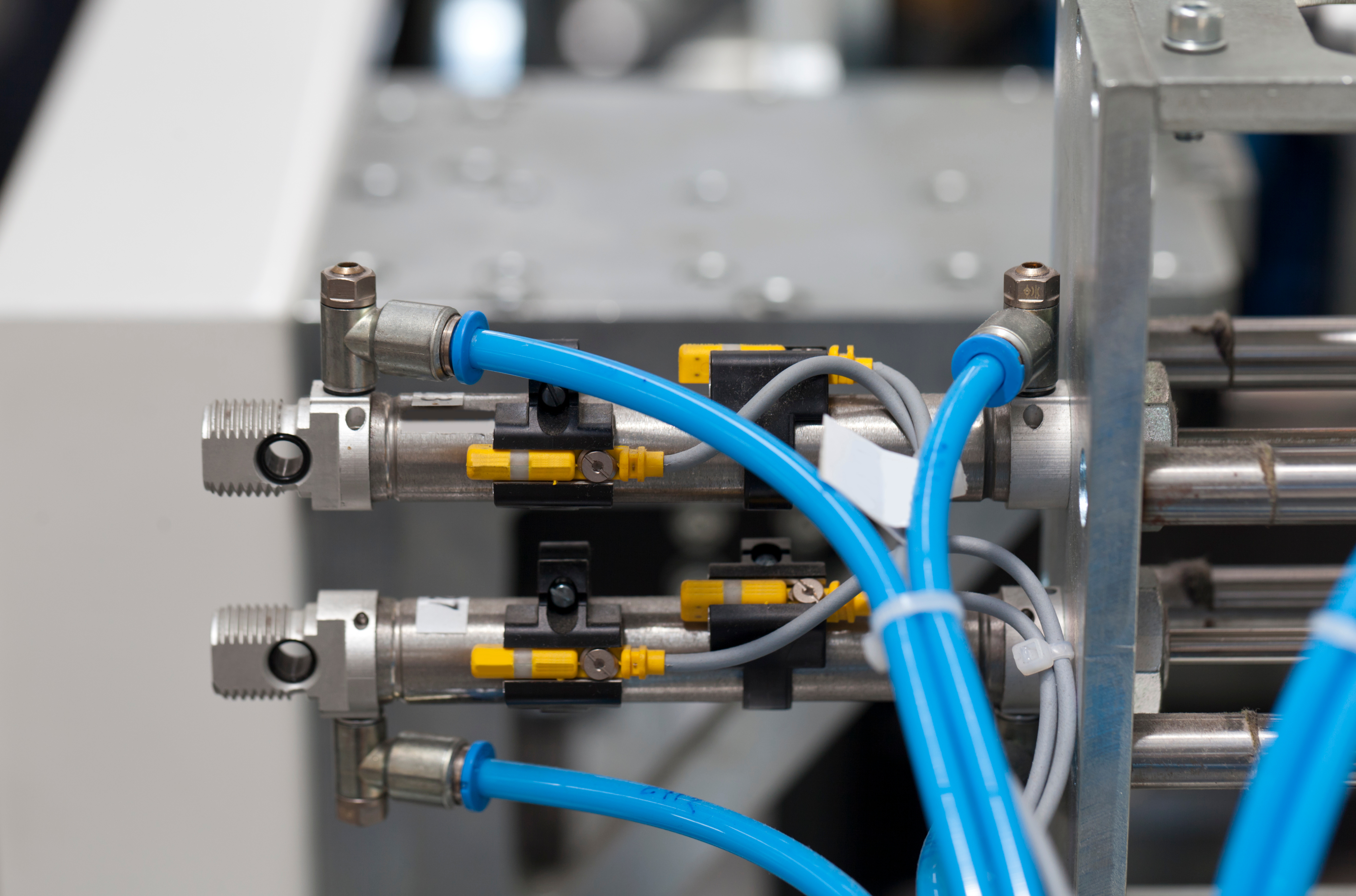 Various pneumatic components are hooked up to a machine. The components feature blue wires that connect to valves.