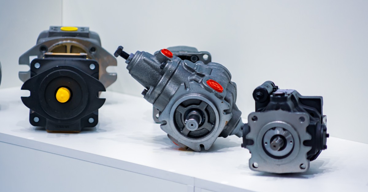 Three different types of hydraulic pumps displayed on a white table, showcasing their various designs and sizes.