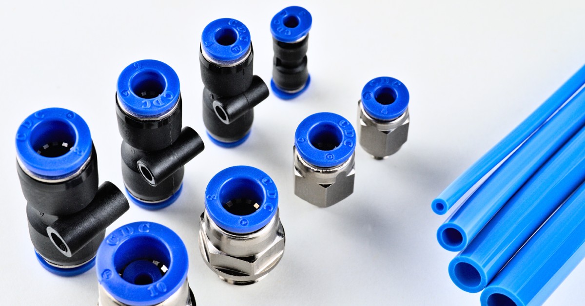 Various plastic and brass push-to-connect fittings are on display. They are in different sizes and blue tubing is next to them.