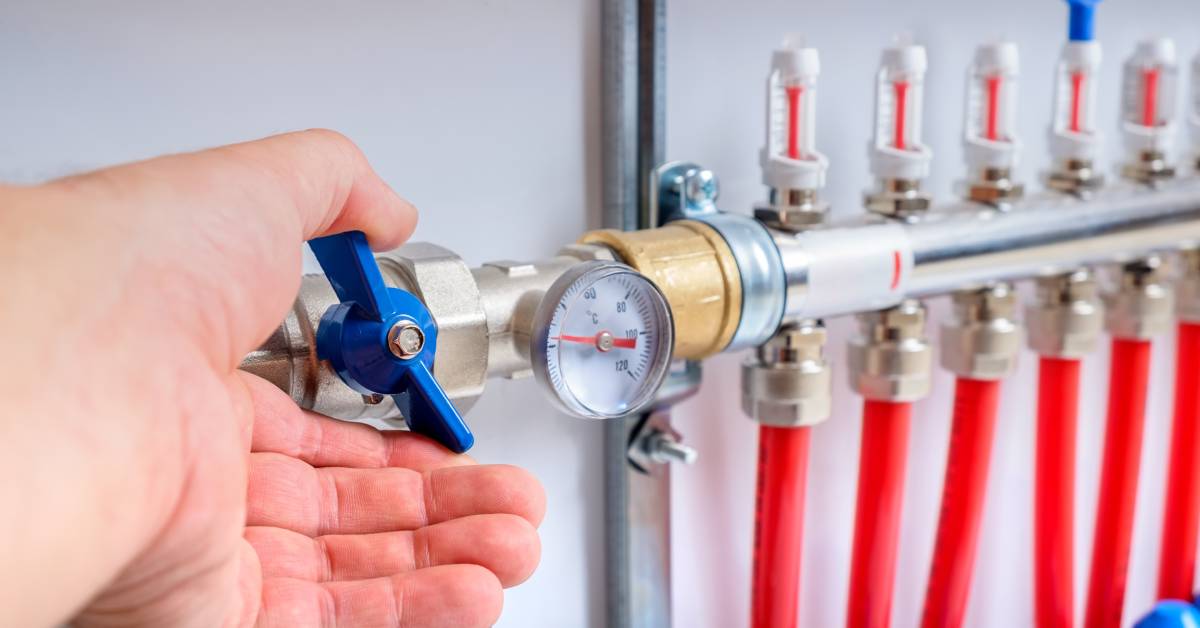 A close-up of a hydraulic system. Someone's hand is opening the hydraulic ball valve, showcasing its operation and design.