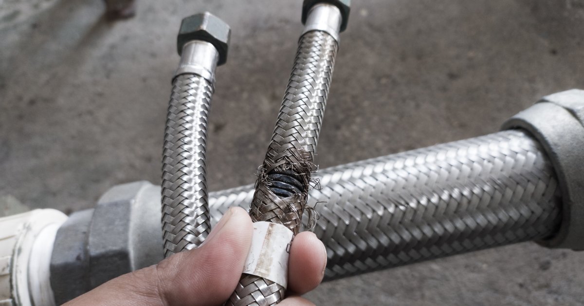 A close-up of a hydraulic hose. The outside of the hose appears to be frayed from damage due to friction.