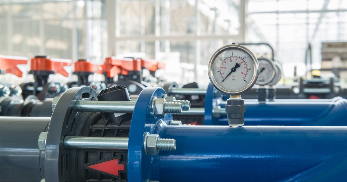 A row of hydraulic systems in front of a window. Each has a pressure gauge and an arrow pointing toward the left.