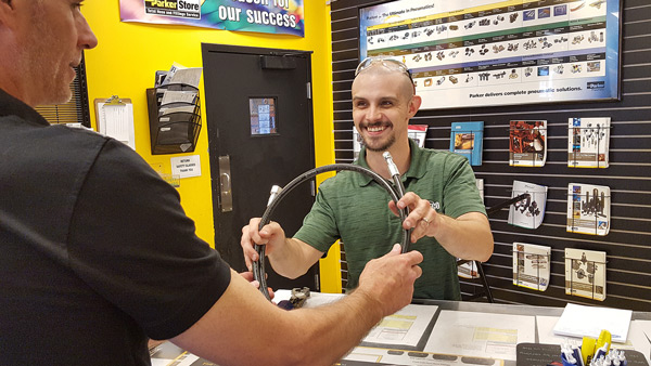 Parker Store representative, handing customer a completed hose assembly. Image